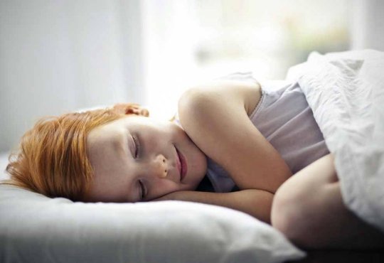 Dobry sen świetnie wpływa na organizm. Na zdjęciu dziewczynka w łóżku.