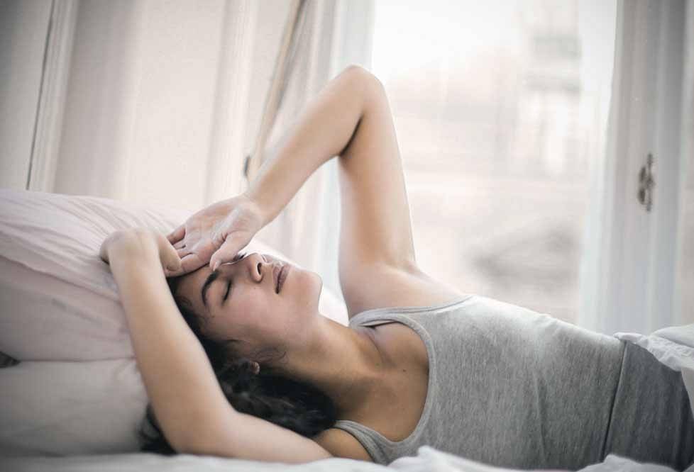 Niedobór snu może generować większy stres. Zdjęcie pokazuje kobietę, która budzi się po nocy.
